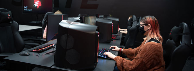 A student playing games in the vault while social distancing and wearing a mask.